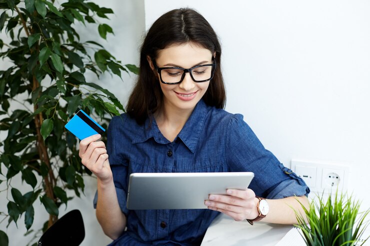 beautiful-young-girl-wearing-blue-shirt-eyeglasses-sitting-with-tablet-freelance-concept-online-shopping-holding-credit-card_355000-1846