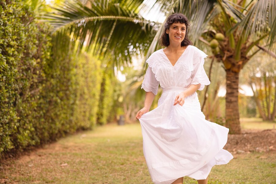 smiling-caucasian-young-brunette-girl-wearing-white-sundress-walks-tropical-garden-alone-summer-morning_197531-32573