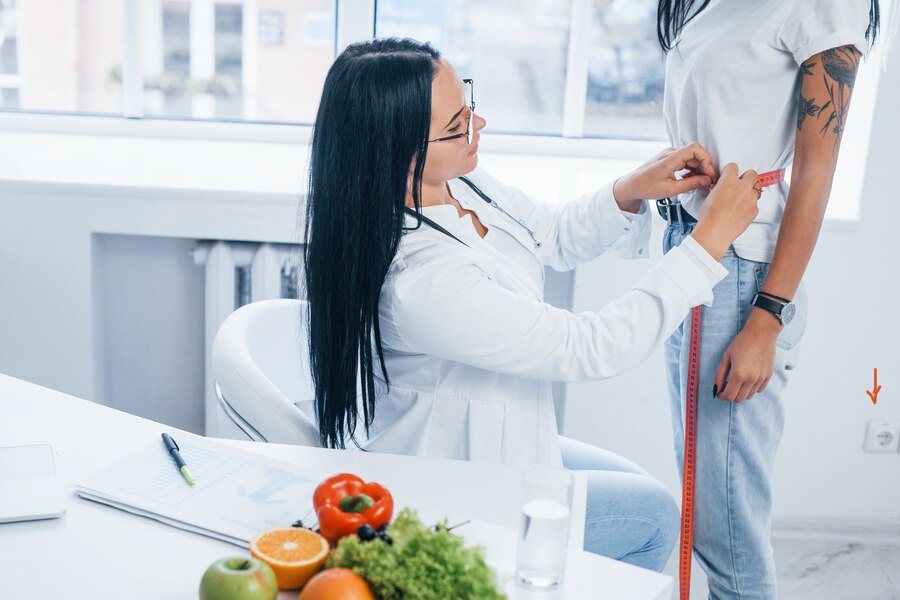 female-nutritionist-measuring-waist-patient-by-tape-indoors-office_146671-29834