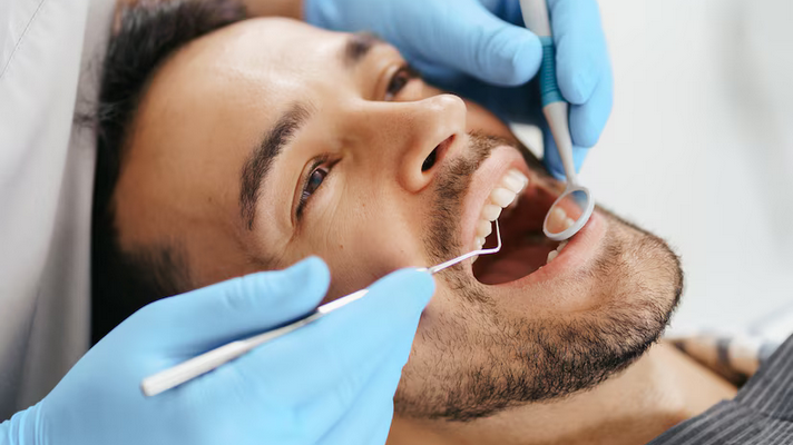 Screenshot 2024-11-26 at 16-16-59 Free Photo Smiling young man sitting in dentist chair while doctor examining his teeth