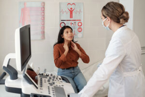 young-hispanic-female-patient-touching-her-thyroid